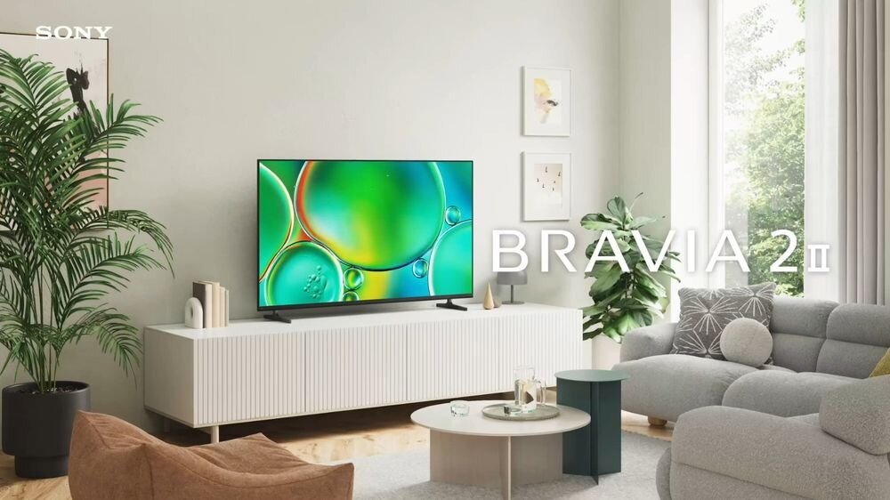 W salonie na białej szafce stoi telewizor z kolorowym wyświetlaczem. Na ekranie widoczny jest napis \'BRAVIA 2 II\', a w rogu znajduje się logo \'SONY\'.