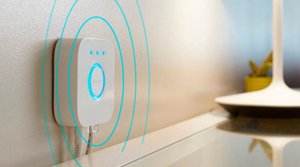 Na ścianie zamontowane jest białe urządzenie z niebieskim podświetleniem i logo \'PHILIPS\'. Obok znajduje się lampa z białym kloszem.