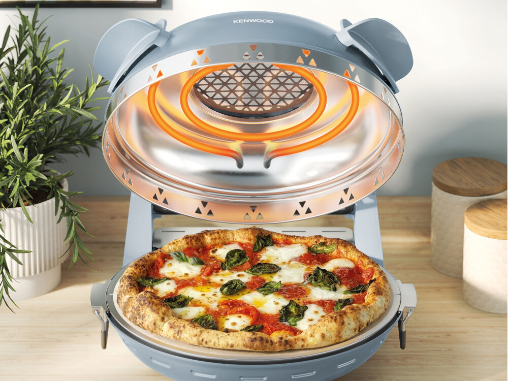 Szary piec do pizzy z otwartą pokrywą, w środku znajduje się pizza z serem, pomidorami i bazylią. Na pokrywie widoczne jest logo \'KENWOOD\'.