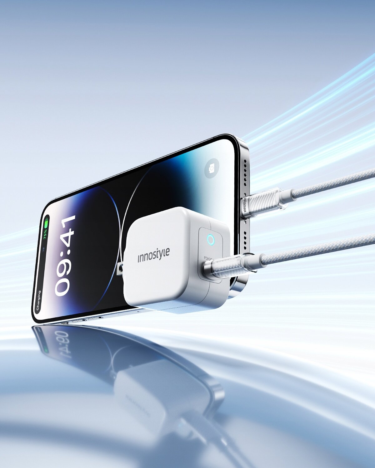 Na obrazie widać smartfon z wyświetlaczem pokazującym godzinę 09:41, do którego podłączona jest ładowarka z logo \'innostyle\'. Kabel USB-C Lightning jest podłączony do ładowarki i telefonu, a tło jest niebieskie z dynamicznymi liniami.