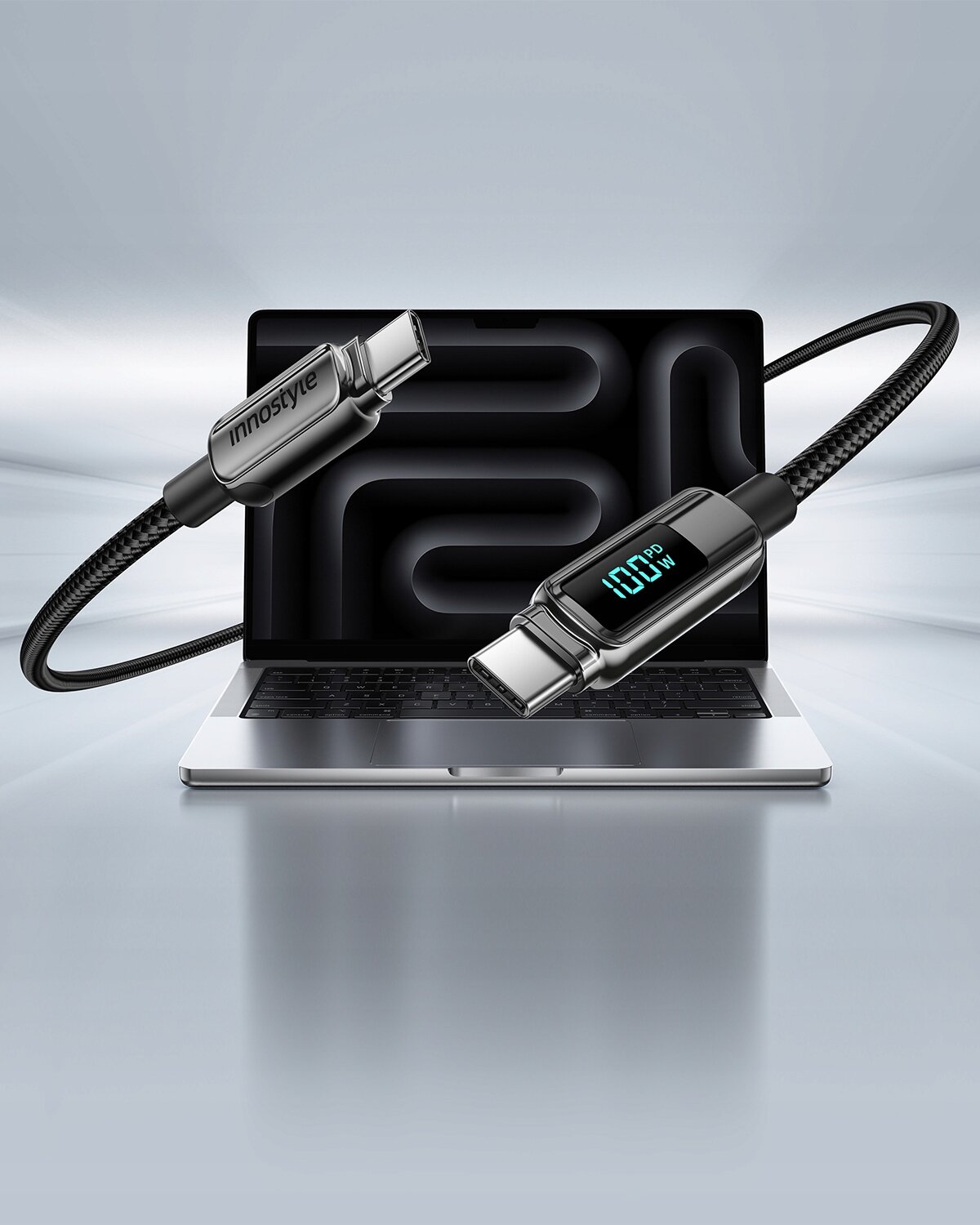 Kabel USB-C z wyświetlaczem pokazującym \'100W\' jest umieszczony na tle otwartego laptopa. Na kablu widoczne jest logo \'innostyle\'.