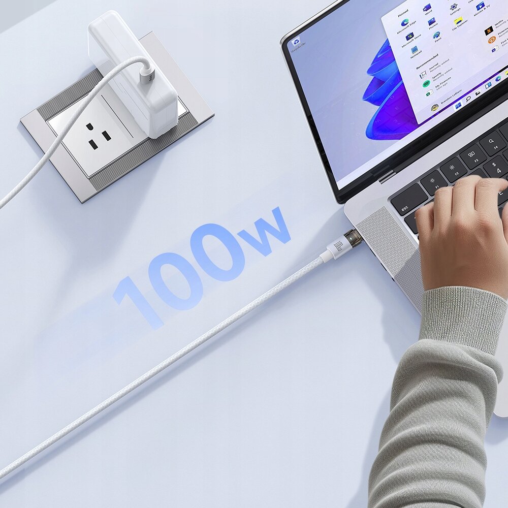 Na obrazie widać laptopa podłączonego do gniazdka za pomocą białego kabla USB-C. Obok kabla widoczny jest napis \'100w\'.
