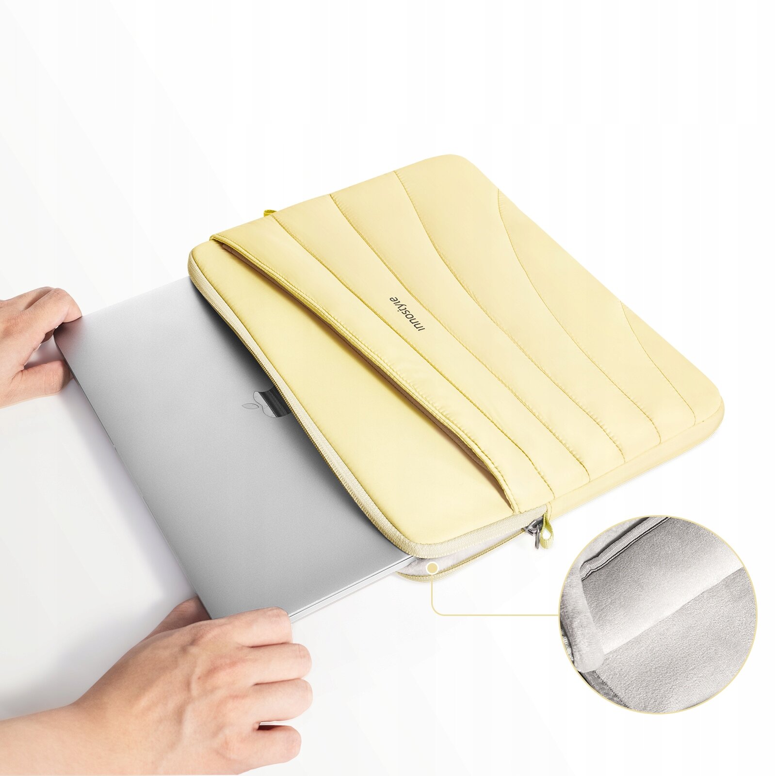 Żółta torba na laptopa z napisem \'Innostyle\' jest otwarta, a obok niej znajduje się laptop. W prawym dolnym rogu widoczny jest powiększony fragment wnętrza torby.