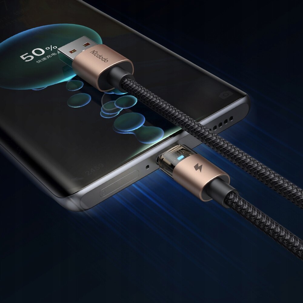 Zdjęcie przedstawia kabel USB-A do USB-C podłączony do smartfona, z widocznym napisem \'Mcdodo\' na wtyczce USB-A oraz ikoną błyskawicy na wtyczce USB-C. Na ekranie smartfona widoczny jest wskaźnik ładowania na poziomie 50%.