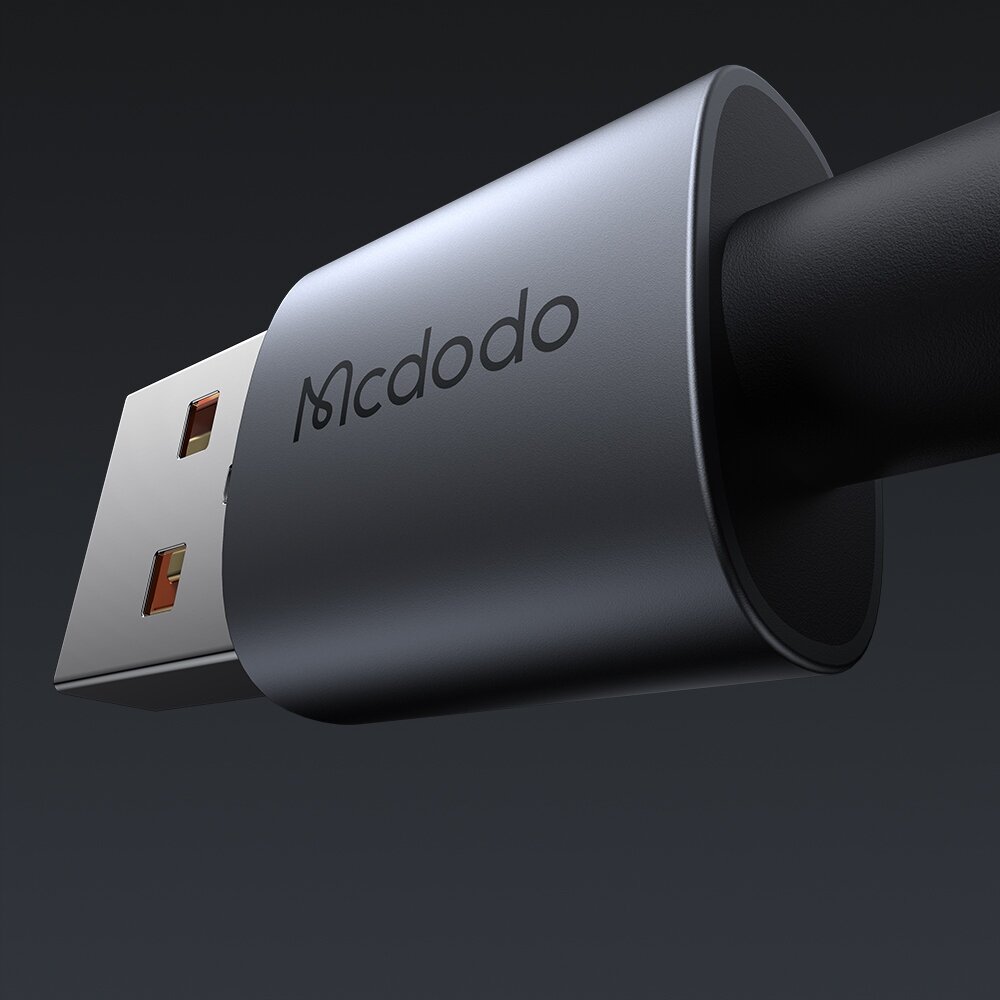 Zbliżenie na metalową końcówkę kabla USB z widocznym napisem \'Mcdodo\' na ciemnym tle.