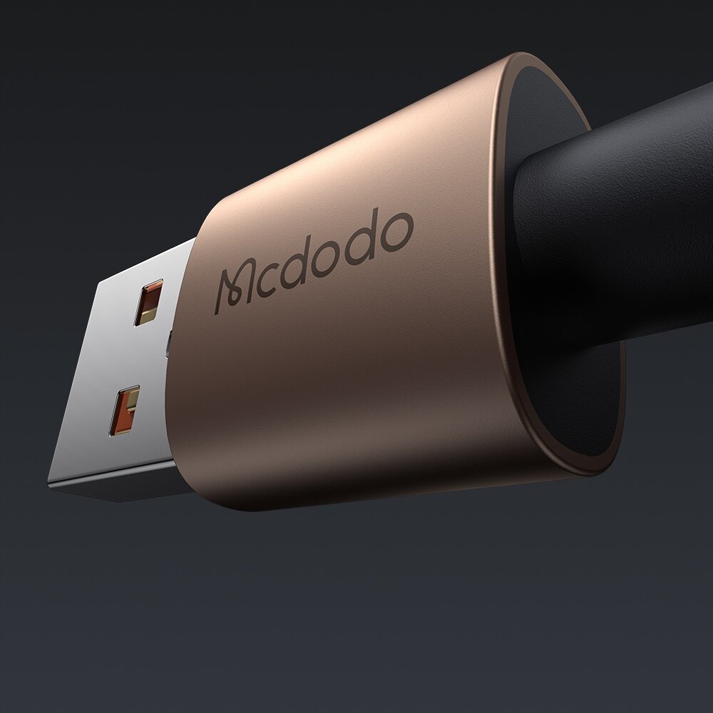 Zbliżenie na złoty wtyk USB z logo \'Mcdodo\' na tle ciemnego gradientu. Kabel jest czarny i wchodzi do obudowy wtyku.