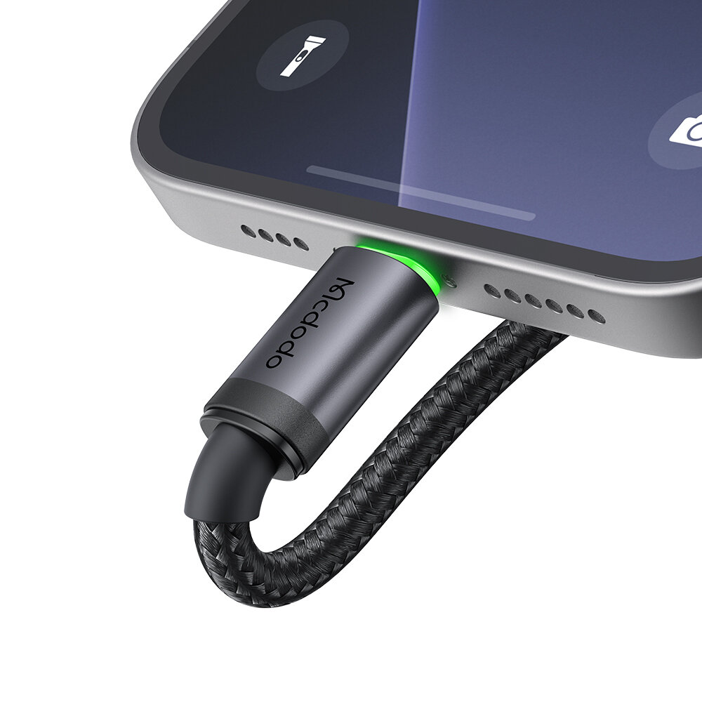 Zbliżenie na kabel USB-C podłączony do urządzenia, z widocznym logo \'Mcdodo\' na wtyczce oraz zielonym podświetleniem wokół złącza.