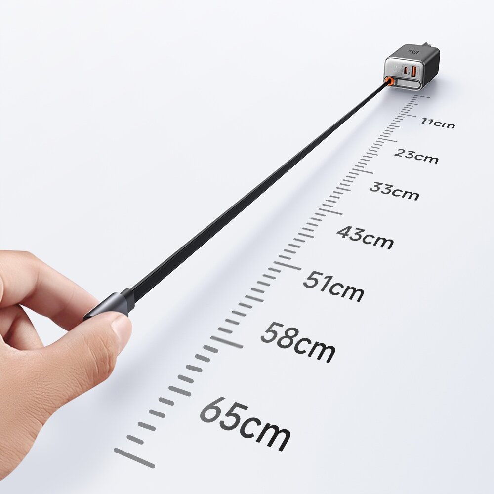 Obraz przedstawia rękę trzymającą kabel, który jest rozciągnięty wzdłuż miarki z oznaczeniami od 11 cm do 65 cm. Na końcu kabla znajduje się ładowarka z dwoma portami USB-C i jednym USB-A.