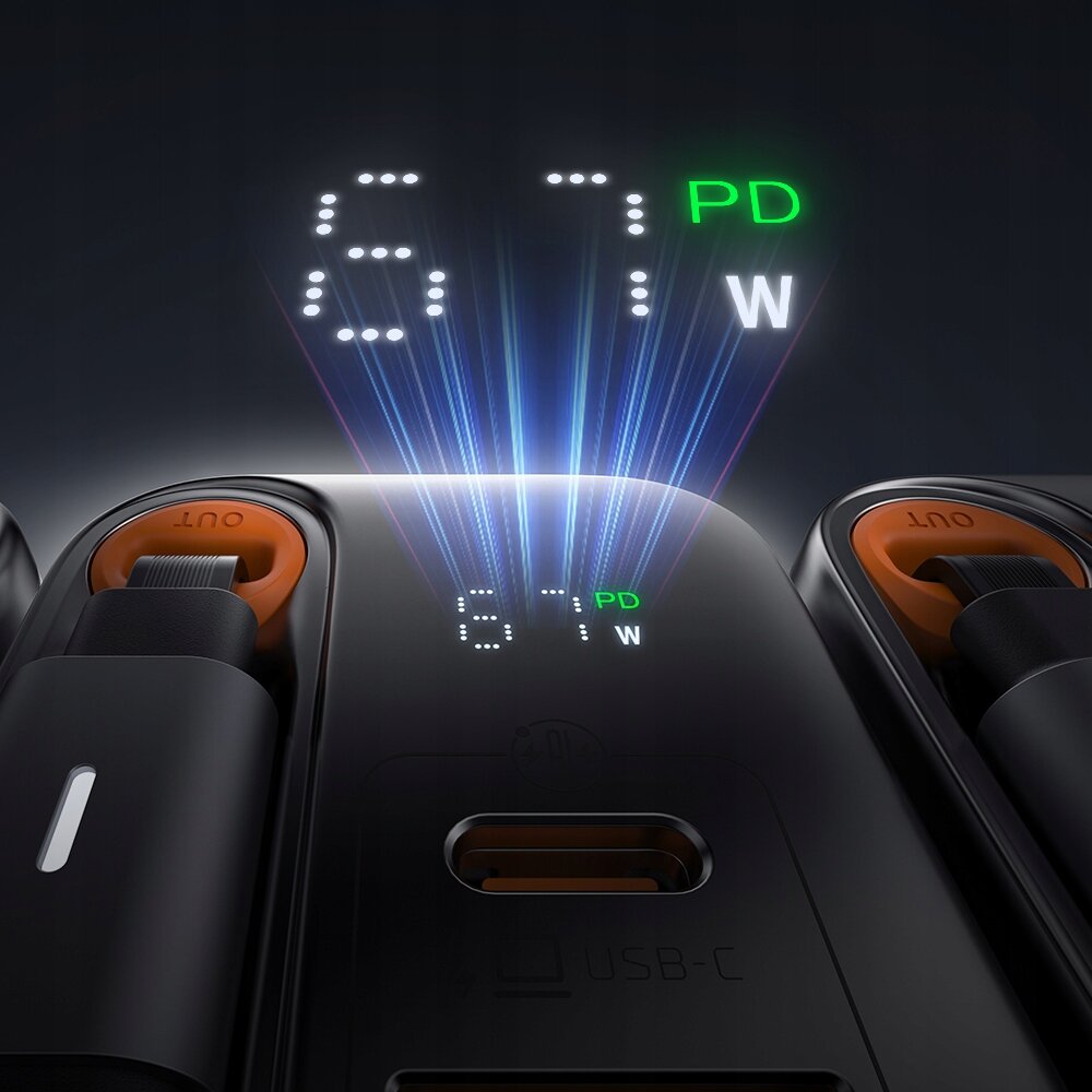 Zdjęcie przedstawia czarną ładowarkę z trzema portami USB-C, na której wyświetlany jest napis \'67 PD W\'. Widoczne są również dwa pomarańczowe elementy z napisem \'OUT\'.