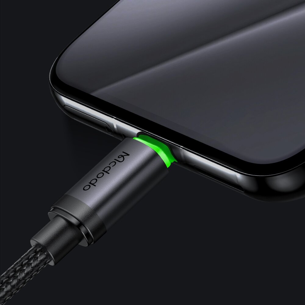 Kabel z logo \'Mcdodo\' podłączony do smartfona, z zielonym podświetleniem przy złączu.