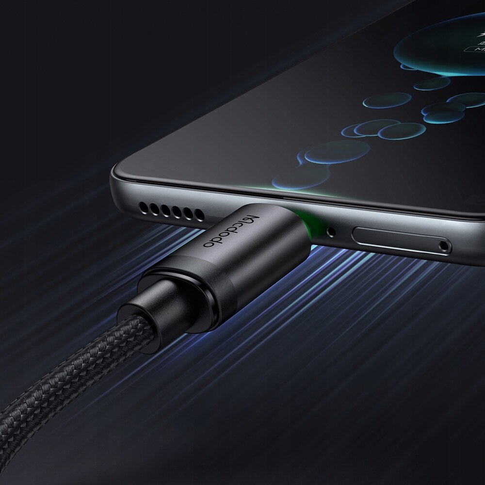 Obraz przedstawia kabel USB podłączony do smartfona, z widocznym logo \'Mcdodo\' na wtyczce. Kabel ma plecioną osłonę, a wokół złącza widać zielone światło.