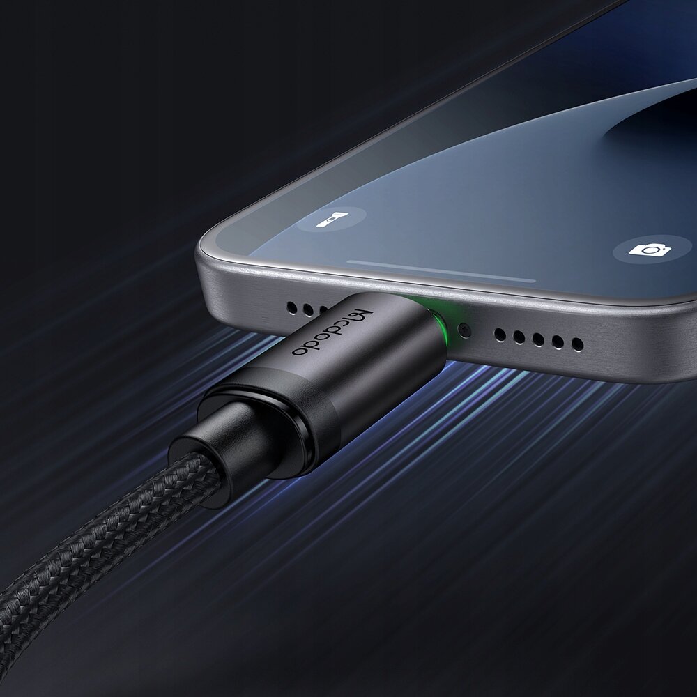 Kabel USB-C podłączony do portu urządzenia z widocznym logo \'Mcdodo\' na wtyczce. Tło jest ciemne, a kabel ma plecioną osłonę.