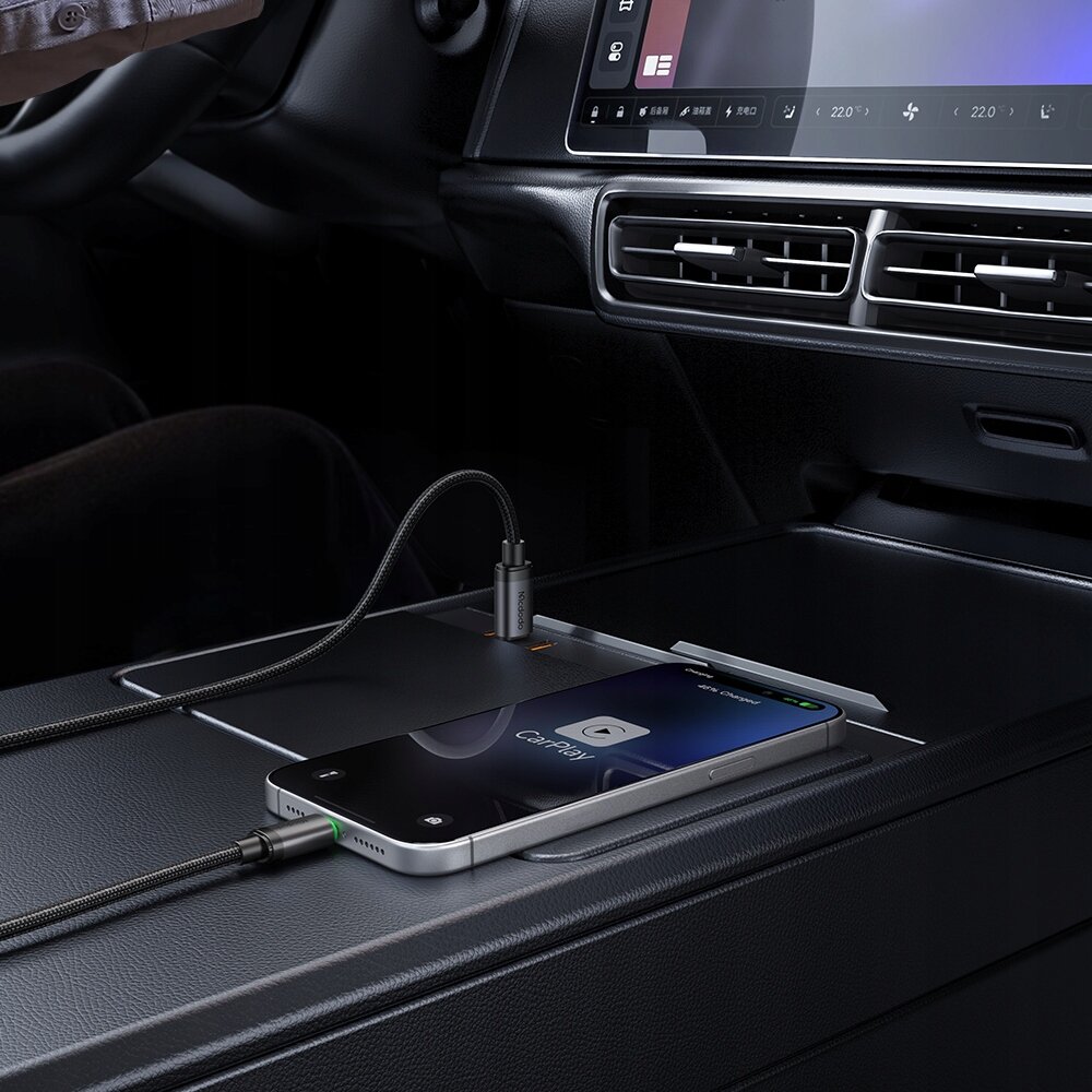 Smartfon z włączonym CarPlay leży na konsoli samochodowej, podłączony do kabla USB-C, który jest wpięty do portu w samochodzie.