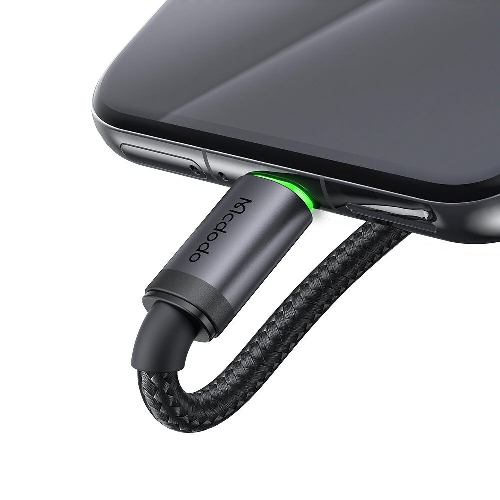 Kabel Micro USB z napisem \'Mcdodo\' podłączony do urządzenia, z zielonym podświetleniem przy złączu.
