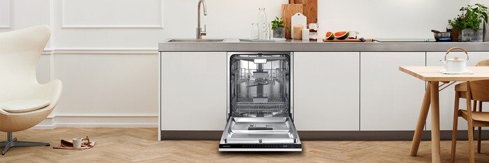 Samsung Zmywarka Dw60m6050bb Lifestyle1 1920 Kuchnia z otwartą zmywarką w zabudowie, widoczne wnętrze zmywarki. Na blacie znajdują się różne przedmioty, w tym deska do krojenia i owoce.