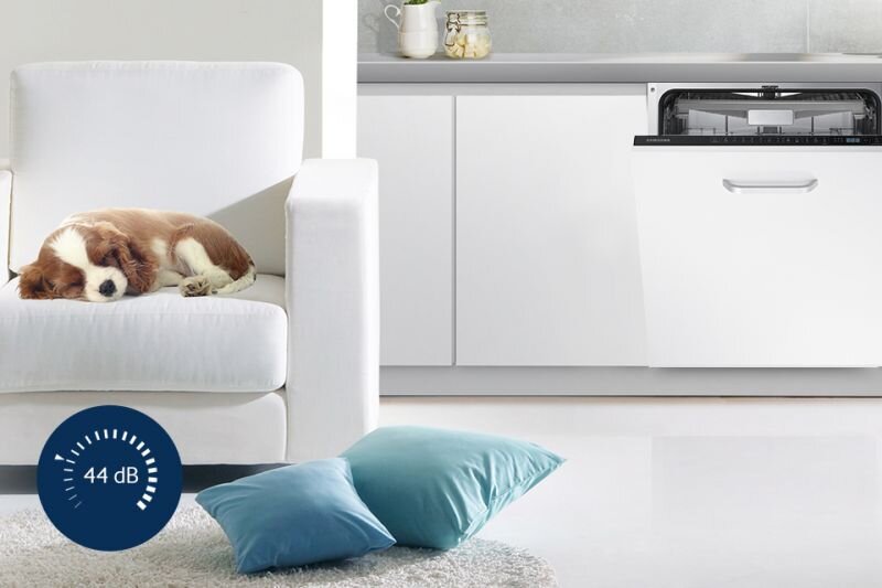 Samsung Pewność i komfort. Cichy tryb pracy Na obrazie widać białą zmywarkę w zabudowie kuchennej z otwartymi drzwiami oraz psa leżącego na białym fotelu. Na dole obrazu znajduje się niebieska ikona z napisem \'44 dB\'.