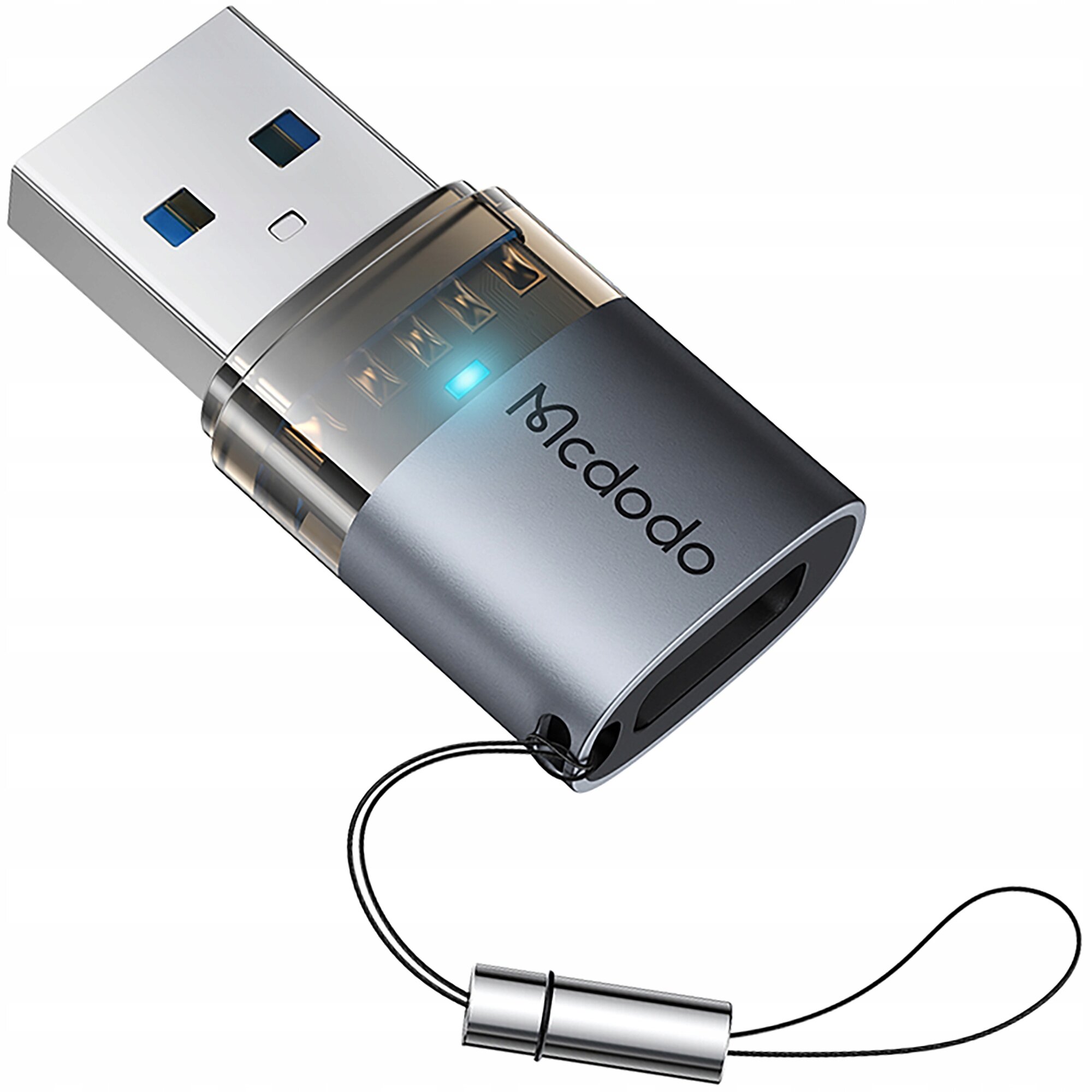 Na obrazie widoczny jest adapter USB z logo \'Mcdodo\', posiadający metaliczną obudowę i niebieski wskaźnik LED. Adapter jest wyposażony w smyczkę do łatwego przenoszenia.