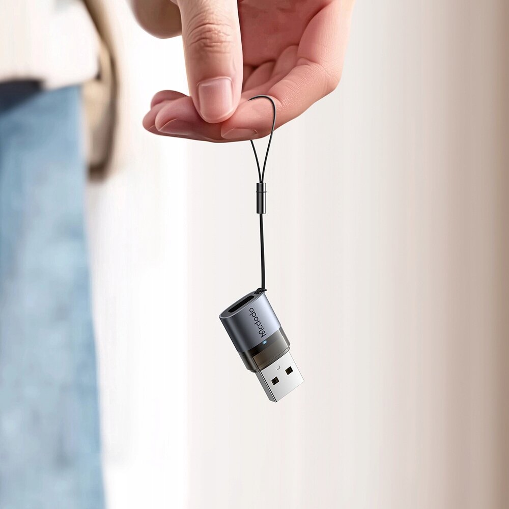 Osoba trzyma adapter USB z napisem \'Mcdodo\' na tle neutralnym.