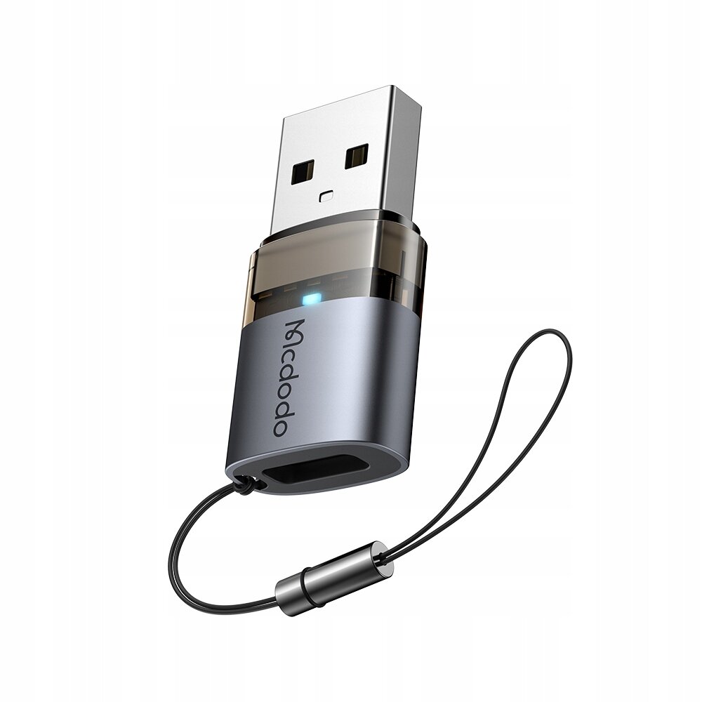 Na obrazie widoczny jest adapter USB z logo \'mcdodo\', posiadający metaliczną obudowę i smyczkę. Adapter ma złącze USB-A oraz port USB-C, a także świecący wskaźnik LED.