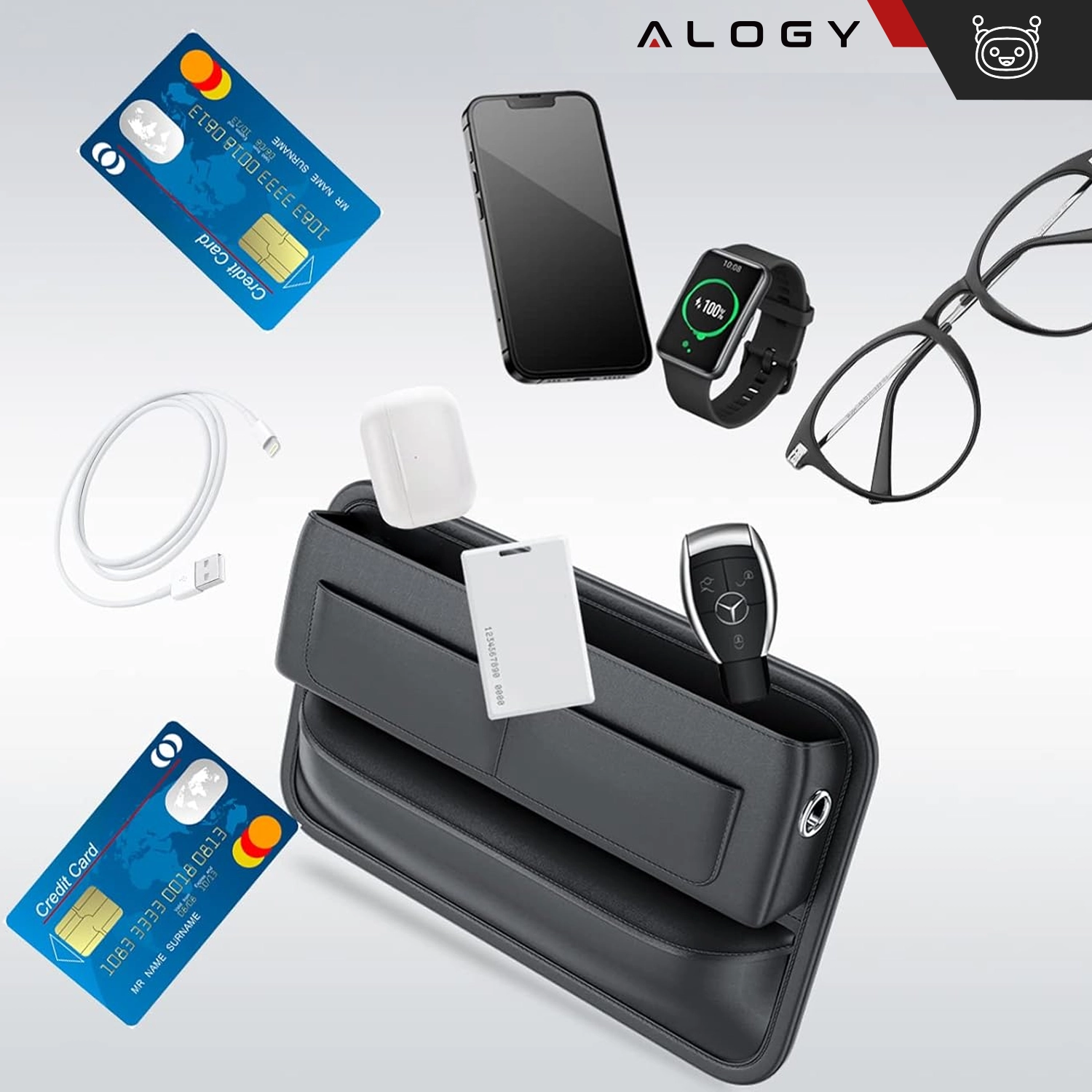 Na obrazie widoczny jest czarny organizer samochodowy z logo Alogy, wypełniony różnymi przedmiotami, takimi jak karty kredytowe, smartfon, zegarek, okulary, kabel USB, etui na słuchawki i kluczyk samochodowy. W tle znajduje się logo Alogy.