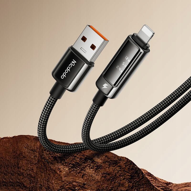 Na obrazie widoczny jest czarny kabel USB z końcówkami USB-A i USB-C, z wyświetlaczem OLED pokazującym wartości 12V, 5V, 2.4A. Na jednej z końcówek znajduje się napis \'Mcdodo\'.