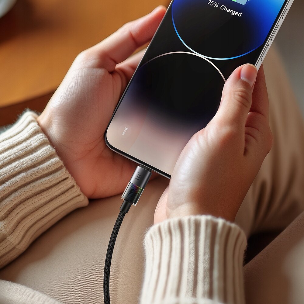 Osoba trzyma smartfon z podłączonym kablem USB, na ekranie widoczny jest napis \'75% Charged\'.