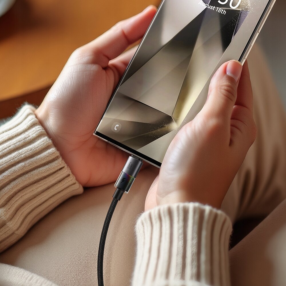 Osoba trzyma smartfon z podłączonym kablem USB-C, na ekranie widoczna jest data \'August 18th\'.
