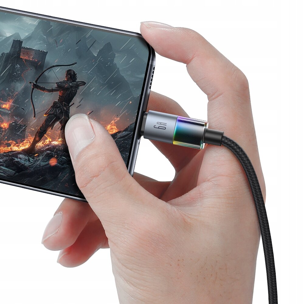 Osoba trzyma smartfon, do którego podłączony jest czarny kabel USB-C z oznaczeniem \'6A\'. Na ekranie telefonu widoczna jest postać z łukiem na tle płonącego krajobrazu.