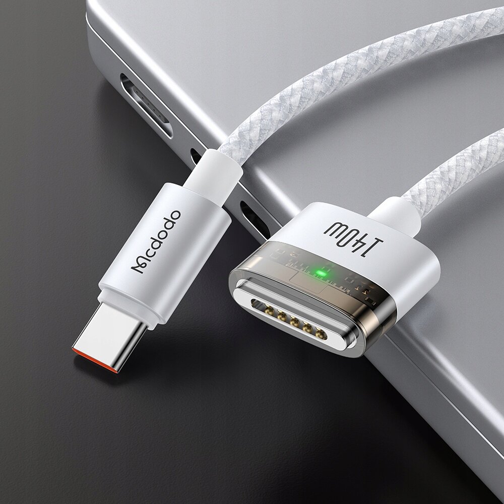 Zdjęcie przedstawia kabel zasilający z końcówką USB-C i magnetycznym złączem, podłączony do laptopa. Na kablu widoczne są napisy \'Mcdodo\' i \'Mcdodo\'.