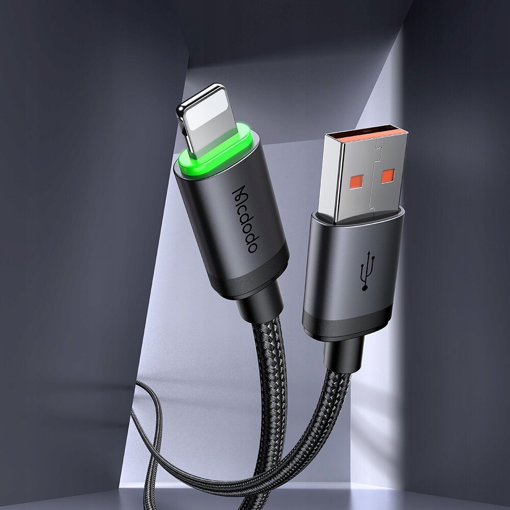 Na obrazie widoczny jest kabel USB z końcówką Lightning, z zielonym podświetleniem i napisem \'Mcdodo\'. Obok znajduje się wtyczka USB z symbolem USB na obudowie.