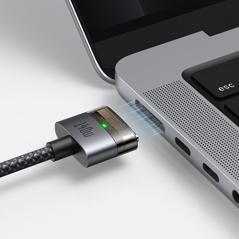 Obraz przedstawia kabel z końcówką magnetyczną z napisem \'140W\', zbliżający się do portu w laptopie. Na końcówce kabla świeci się zielona dioda.