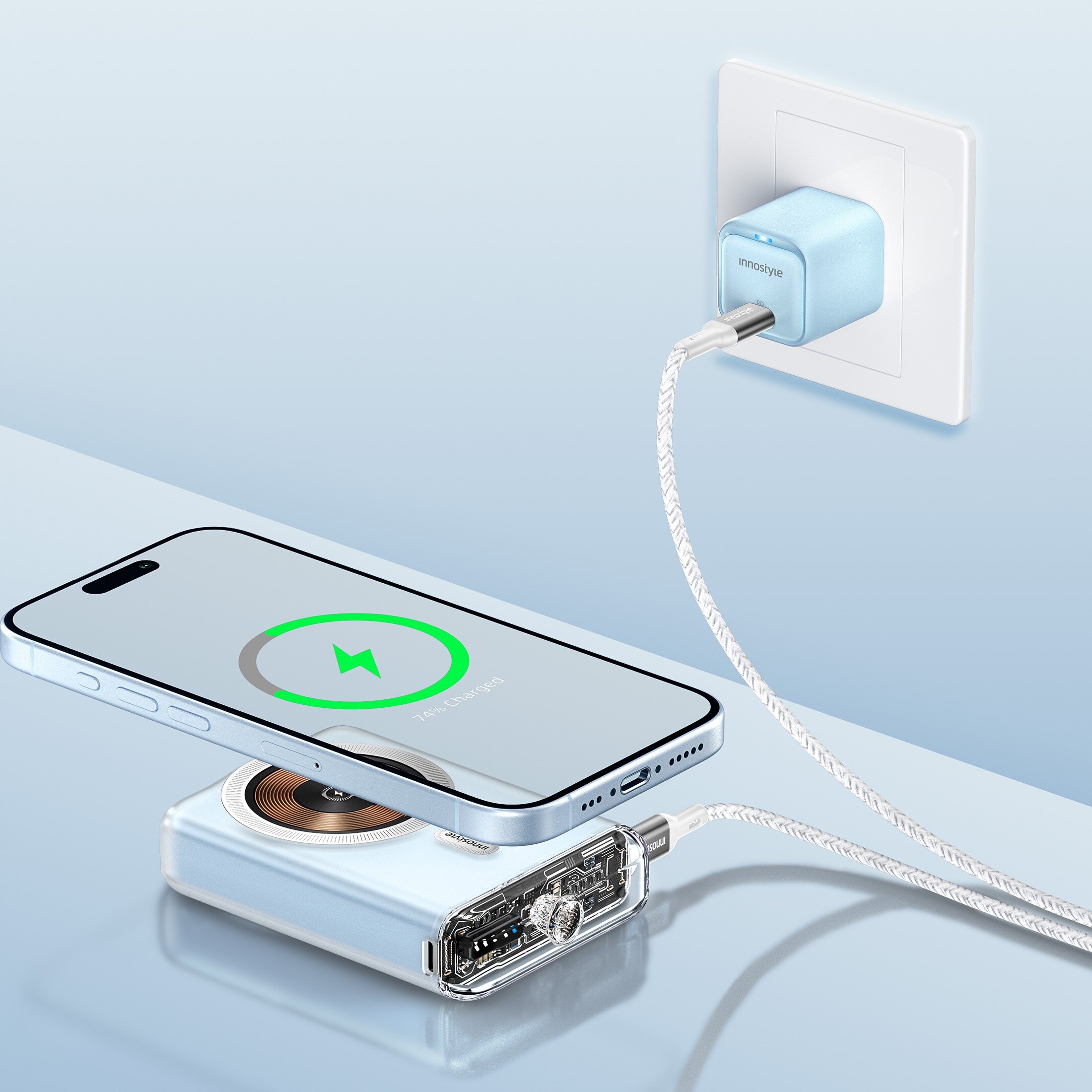 Na obrazie widać telefon leżący na powerbanku, który jest podłączony do gniazdka za pomocą kabla. Na ekranie telefonu widoczna jest ikona ładowania oraz napis \'Charging\'.