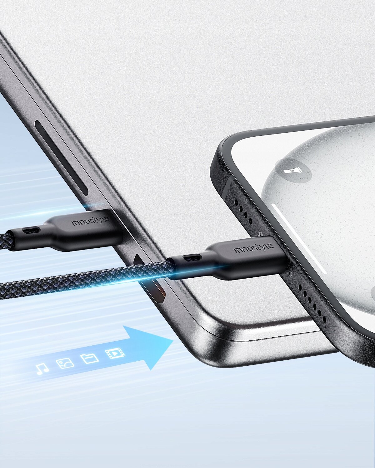 Zdjęcie przedstawia kabel USB-C podłączony do dwóch urządzeń elektronicznych, z widocznym napisem \'innostyle\' na wtyczkach. W tle znajduje się niebieska strzałka z ikonami muzyki, zdjęć i wideo.
