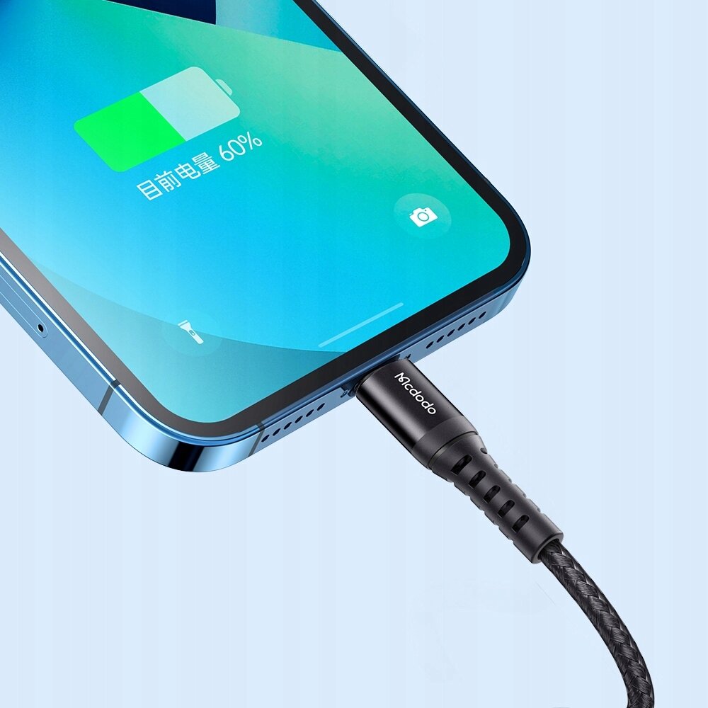 Zbliżenie na telefon z podłączonym kablem USB-C Lightning, na ekranie widoczny jest wskaźnik ładowania z napisem \'当前电量 60%\'. Na wtyczce kabla widoczne jest logo \'Mcdodo\'.