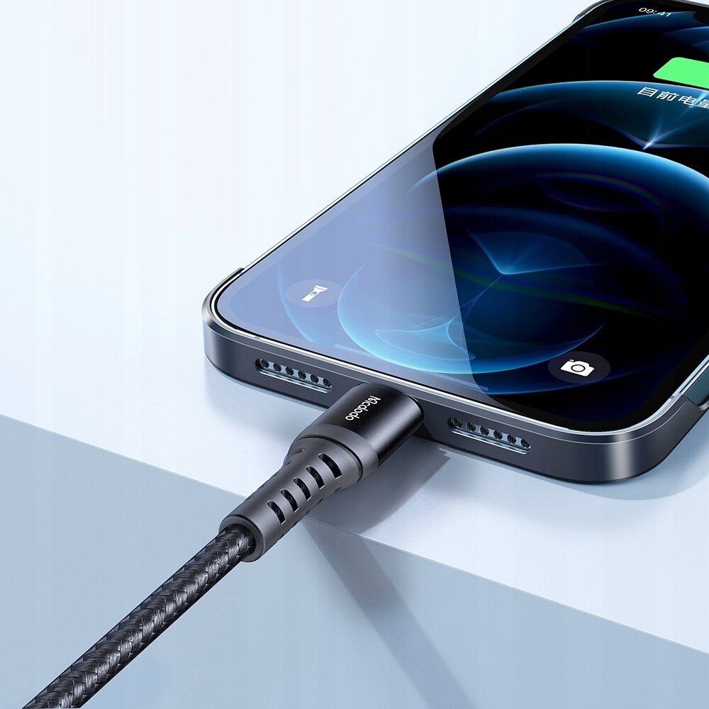 Na obrazie widać smartfon z podłączonym kablem USB-C, na którym widnieje napis \'Mcdodo\'. Ekran telefonu pokazuje ikonę baterii z zielonym wskaźnikiem ładowania.