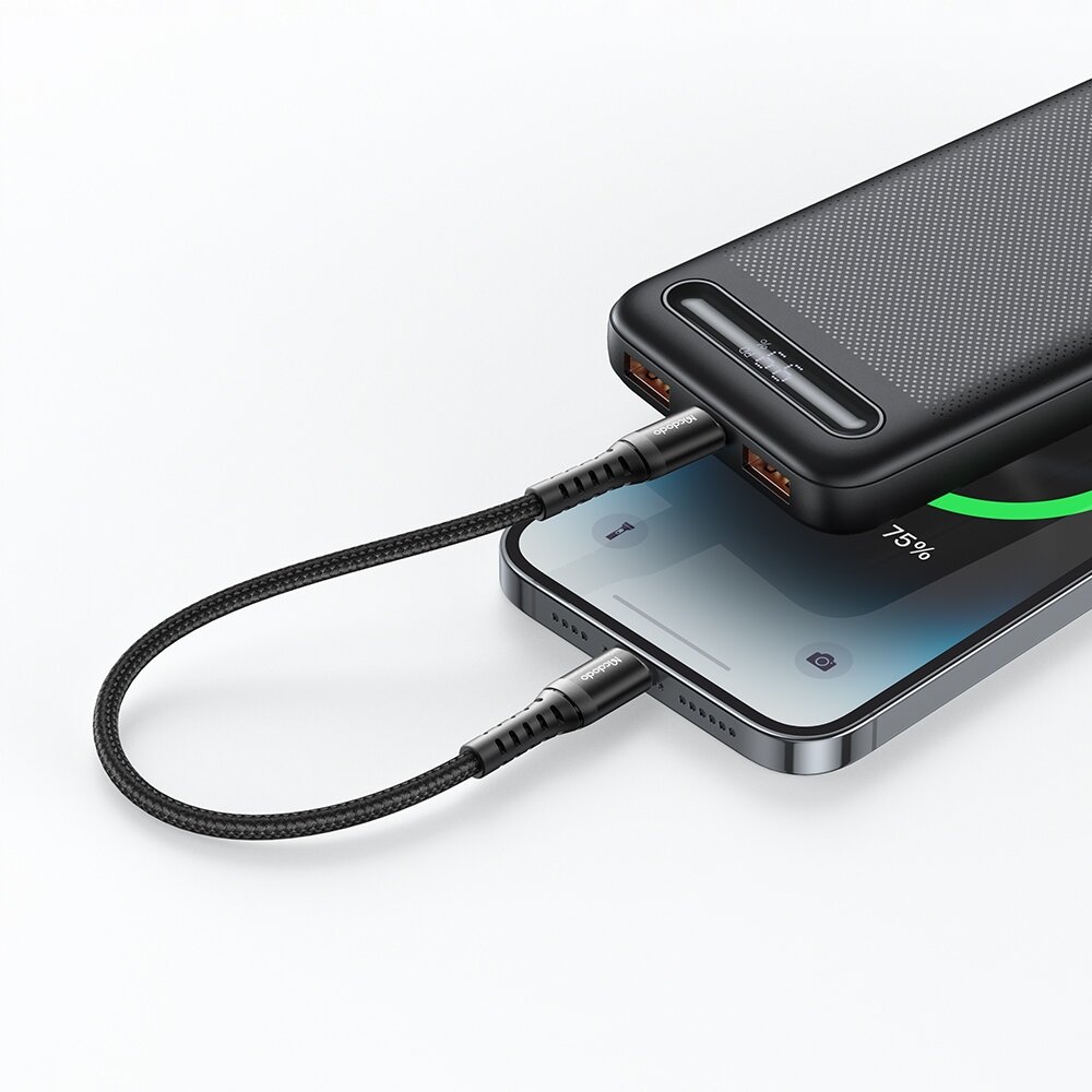 Na obrazie widać smartfon podłączony do powerbanku za pomocą czarnego kabla USB-C. Ekran smartfona pokazuje ikonę ładowania z poziomem naładowania 75%.