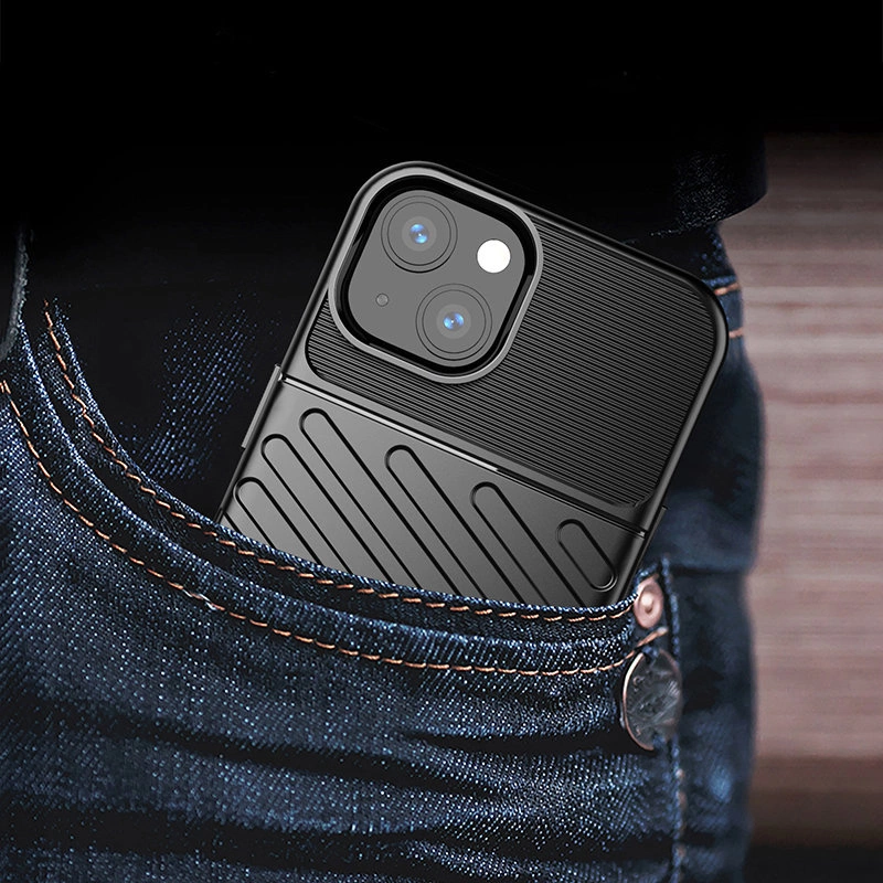 Telefon w czarnym etui z widocznymi dwoma obiektywami aparatu wystaje z kieszeni dżinsów. Etui ma teksturowaną powierzchnię z poziomymi i ukośnymi liniami.