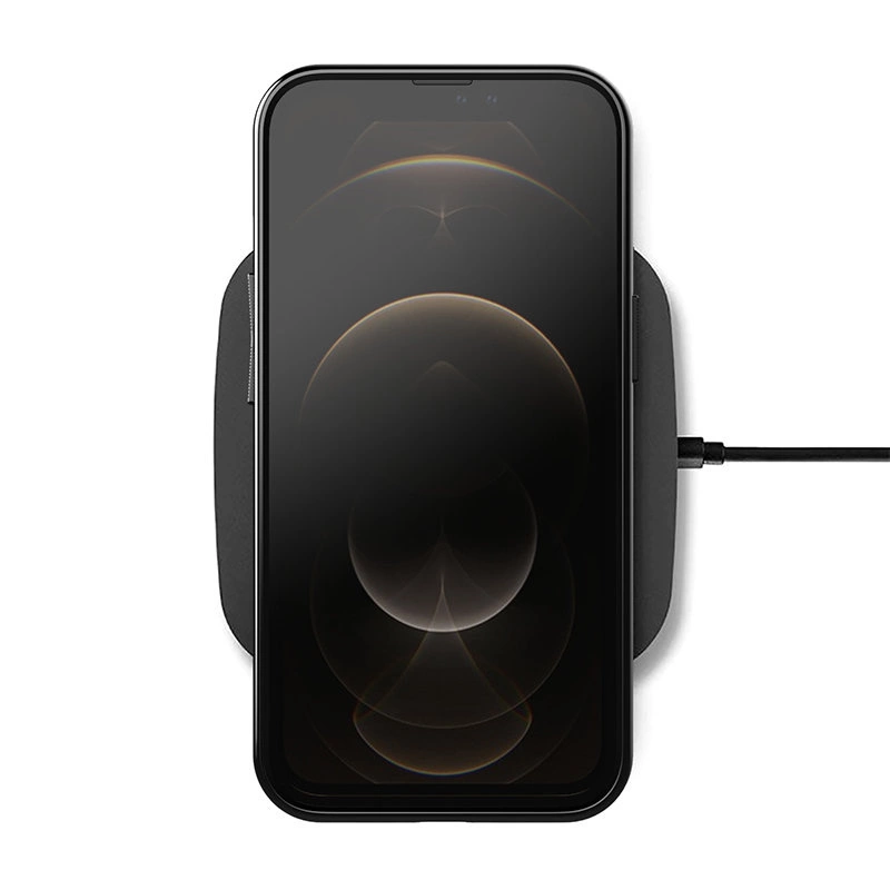 Na obrazie widoczny jest smartfon leżący na ładowarce bezprzewodowej, z wyświetlaczem pokazującym abstrakcyjny wzór. Ładowarka jest podłączona kablem z boku.