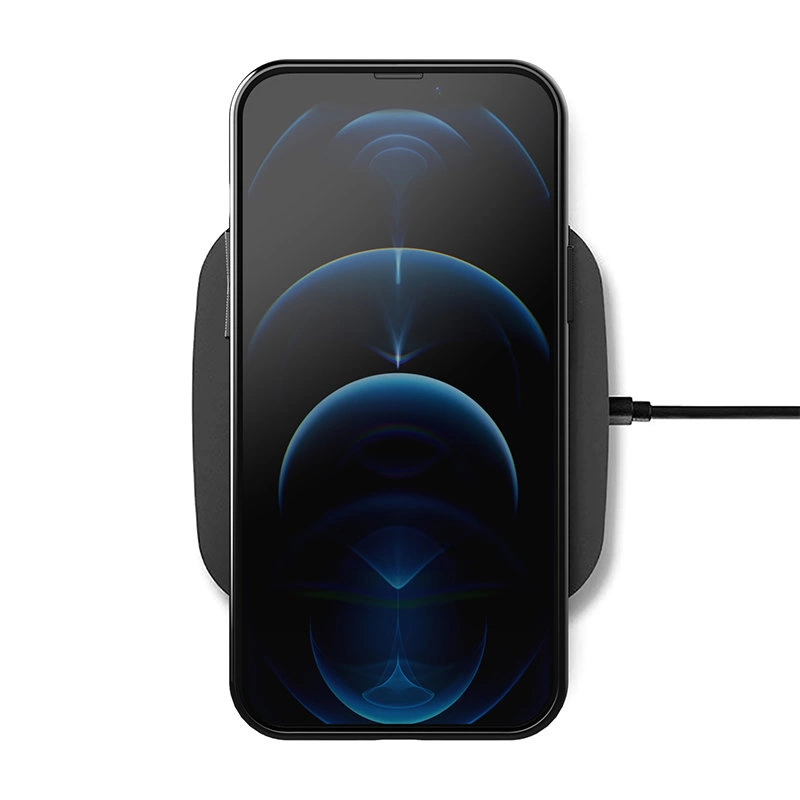 Na obrazie widać smartfon leżący na bezprzewodowej ładowarce, z wyświetlaczem pokazującym abstrakcyjny wzór w odcieniach niebieskiego. Ładowarka jest podłączona do źródła zasilania za pomocą kabla.