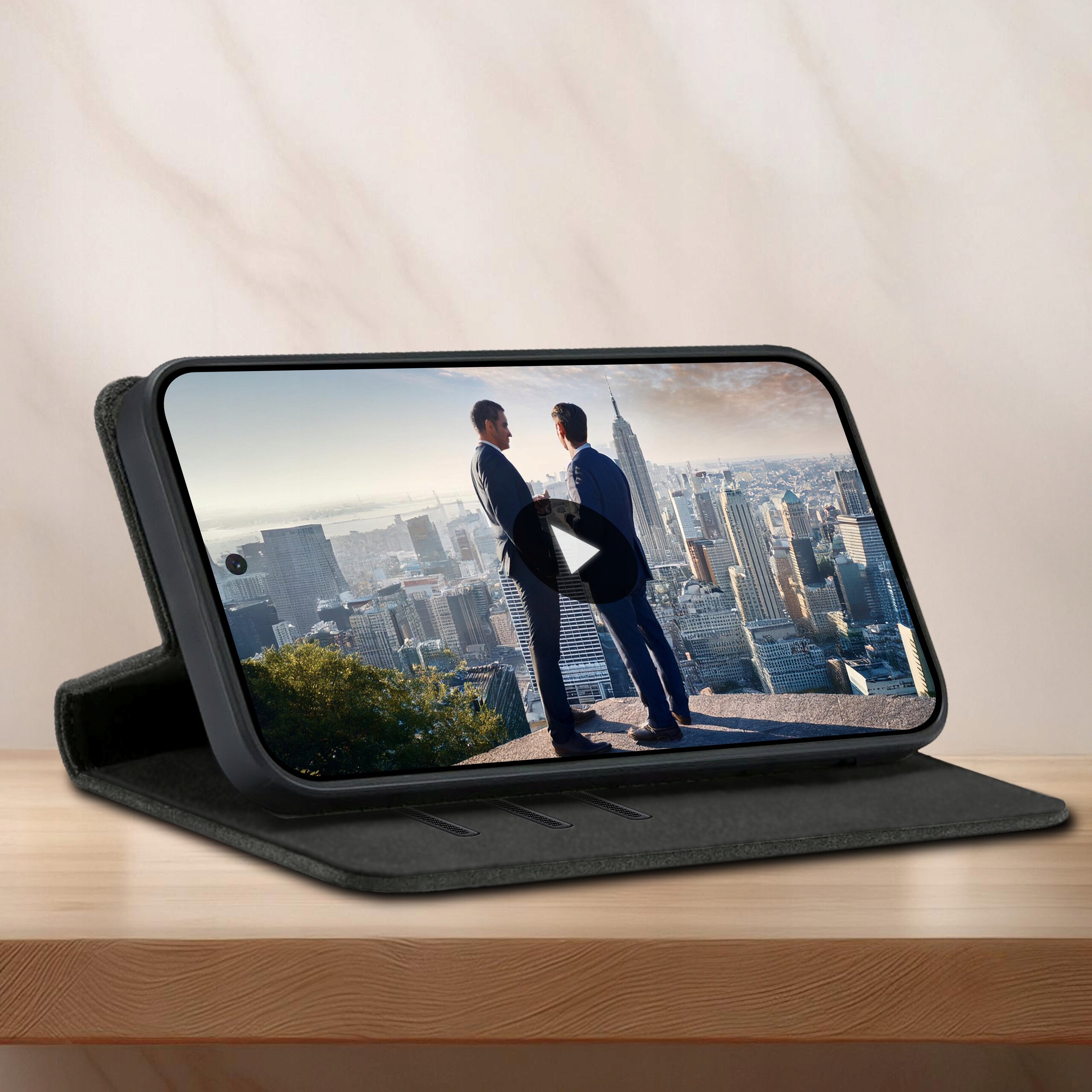Etui z klapką do telefonu Motorola G34 5G, ustawione w pozycji stojącej na drewnianej powierzchni, z wyświetlaczem pokazującym dwóch mężczyzn na tle panoramy miasta.