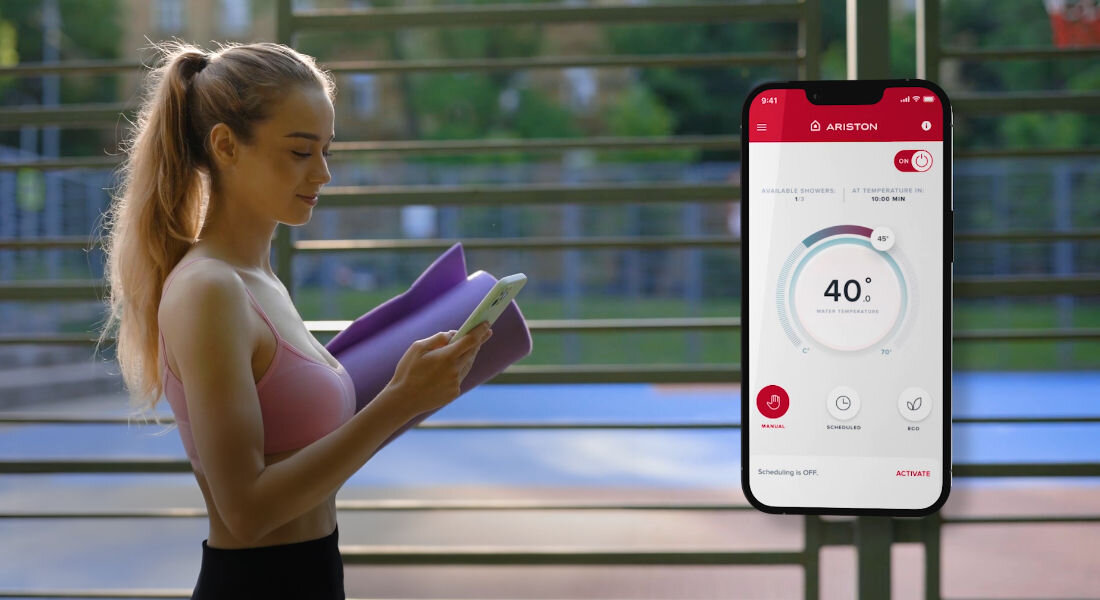 Osoba trzymająca telefon i matę do ćwiczeń, obok widoczny ekran aplikacji z logo ARISTON, pokazujący temperaturę 40°C.