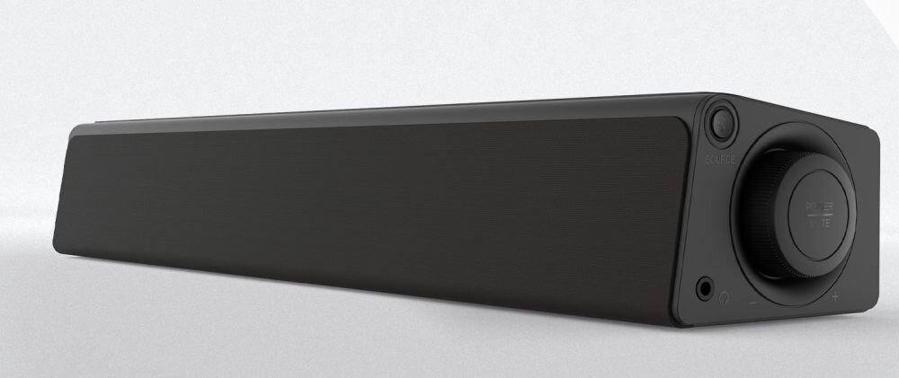 Czarny soundbar o prostokątnym kształcie z widocznym pokrętłem i przyciskiem na jednym z końców. Obudowa jest gładka, a na panelu znajduje się gniazdo audio.