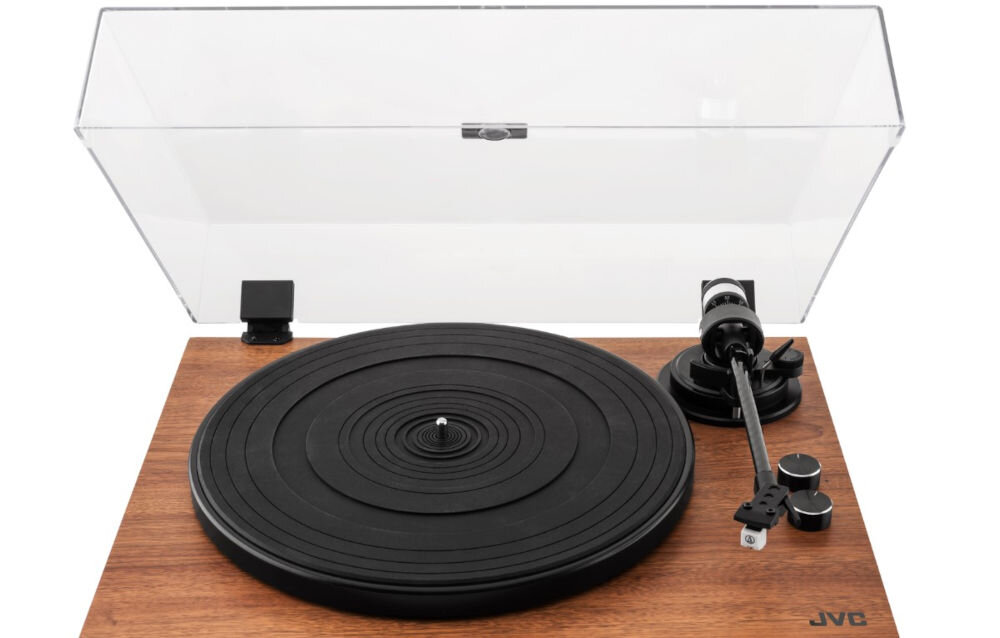 Gramofon z drewnianą podstawą i czarnym talerzem, z przezroczystą pokrywą. Widoczne logo JVC.