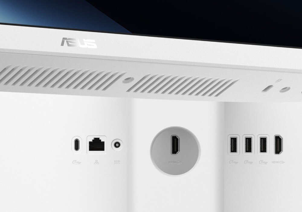 Obraz przedstawia tylną część białego komputera z widocznymi portami: USB, HDMI, Ethernet oraz logo ASUS na górze. Widać również otwory wentylacyjne.