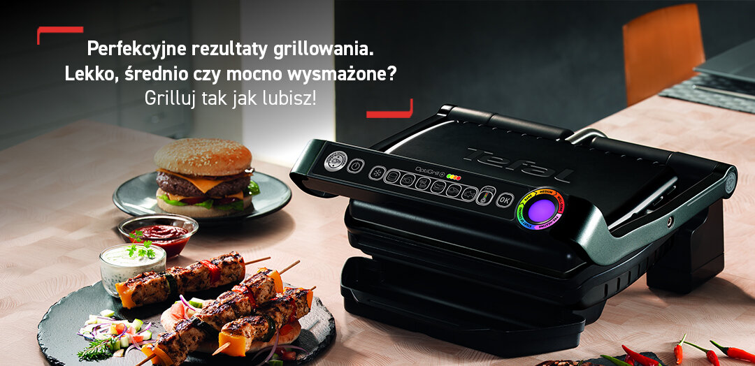 Grill elektryczny Tefal GC7168 na blacie kuchennym, obok talerz z burgerem i szaszłykami.