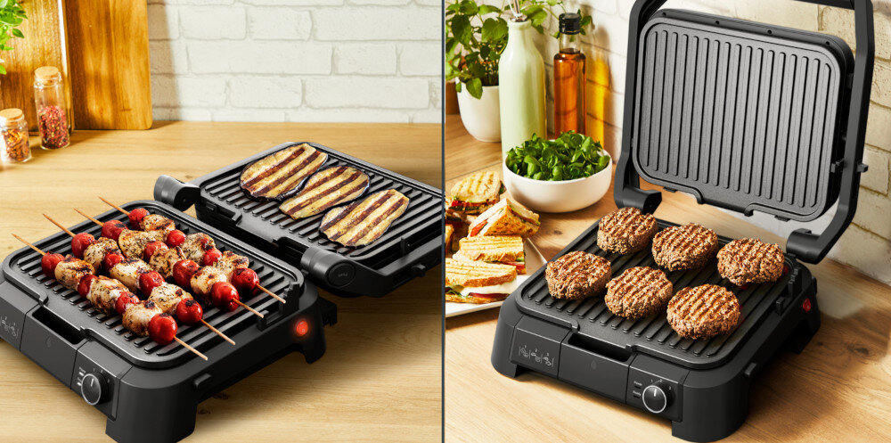 Na obrazie widoczny jest grill elektryczny z otwartą pokrywą, na którym grillowane są szaszłyki i mięso. W tle znajdują się przyprawy i zioła w doniczkach.
