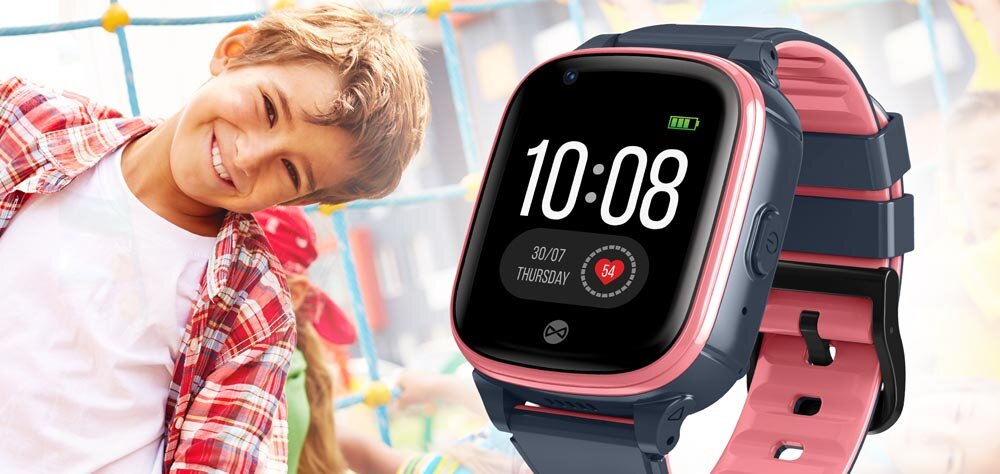 Smartwatch z różowym paskiem i czarnym ekranem wyświetlającym godzinę 10:08, datę 30/07, dzień tygodnia Thursday oraz ikonę baterii. W tle widoczna jest postać dziecka na placu zabaw.