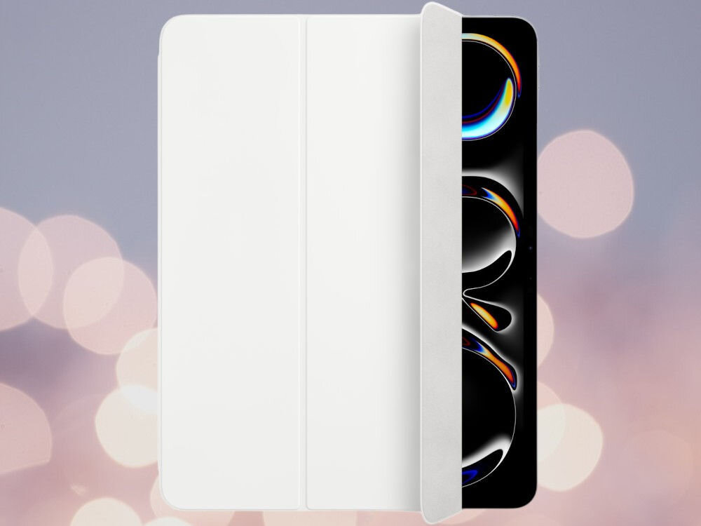 Białe etui na tablet z widoczną częścią ekranu urządzenia, na którym wyświetlane są kolorowe wzory. Tło jest rozmyte z jasnymi, okrągłymi światłami.