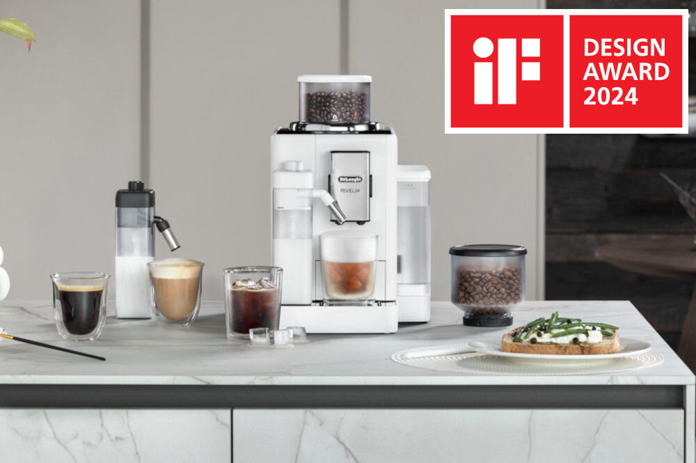 Na blacie kuchennym znajduje się ekspres do kawy Delonghi Rivelia z filiżanką kawy oraz różnymi napojami i przekąską. W prawym górnym rogu widnieje logo \'iF DESIGN AWARD 2024\'.