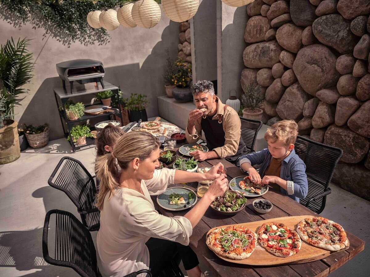 Piec do pizzy WITT Etna Rotante 16 Czarny, pizza, piec, ogród, wypiek, Rodzina jedząca wspólnie pizzę w ogrodzie.